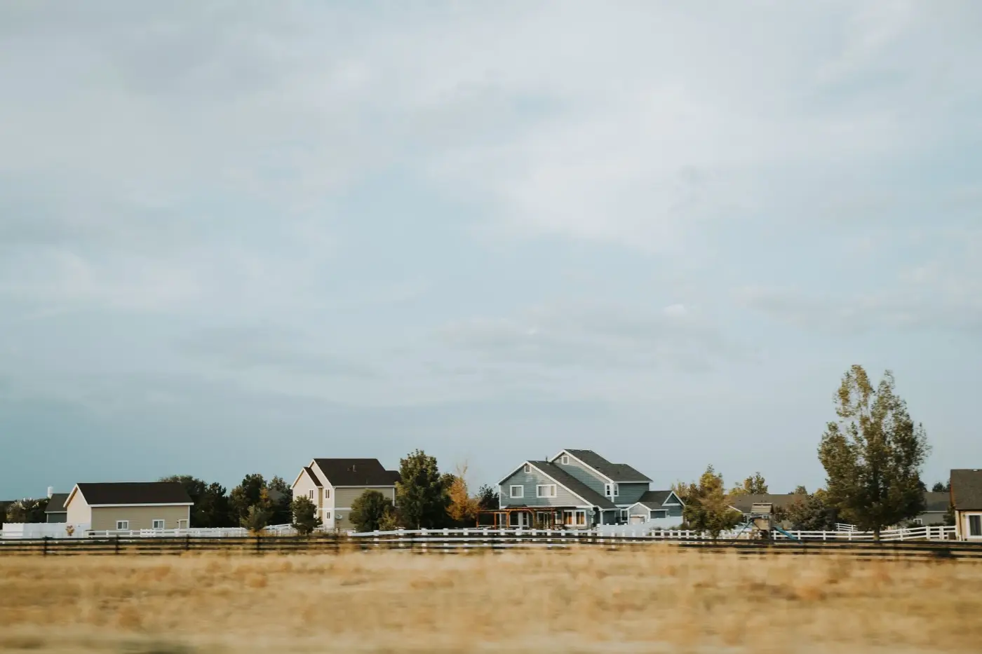 Residential acreage property with homes, fencing, and a wide open sky